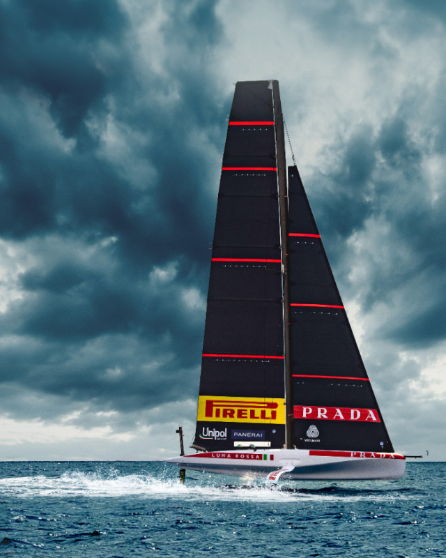 The caravel Luna Rossa sailing on the high seas with the Pirelli logo displayed and cloudy skies in the background.