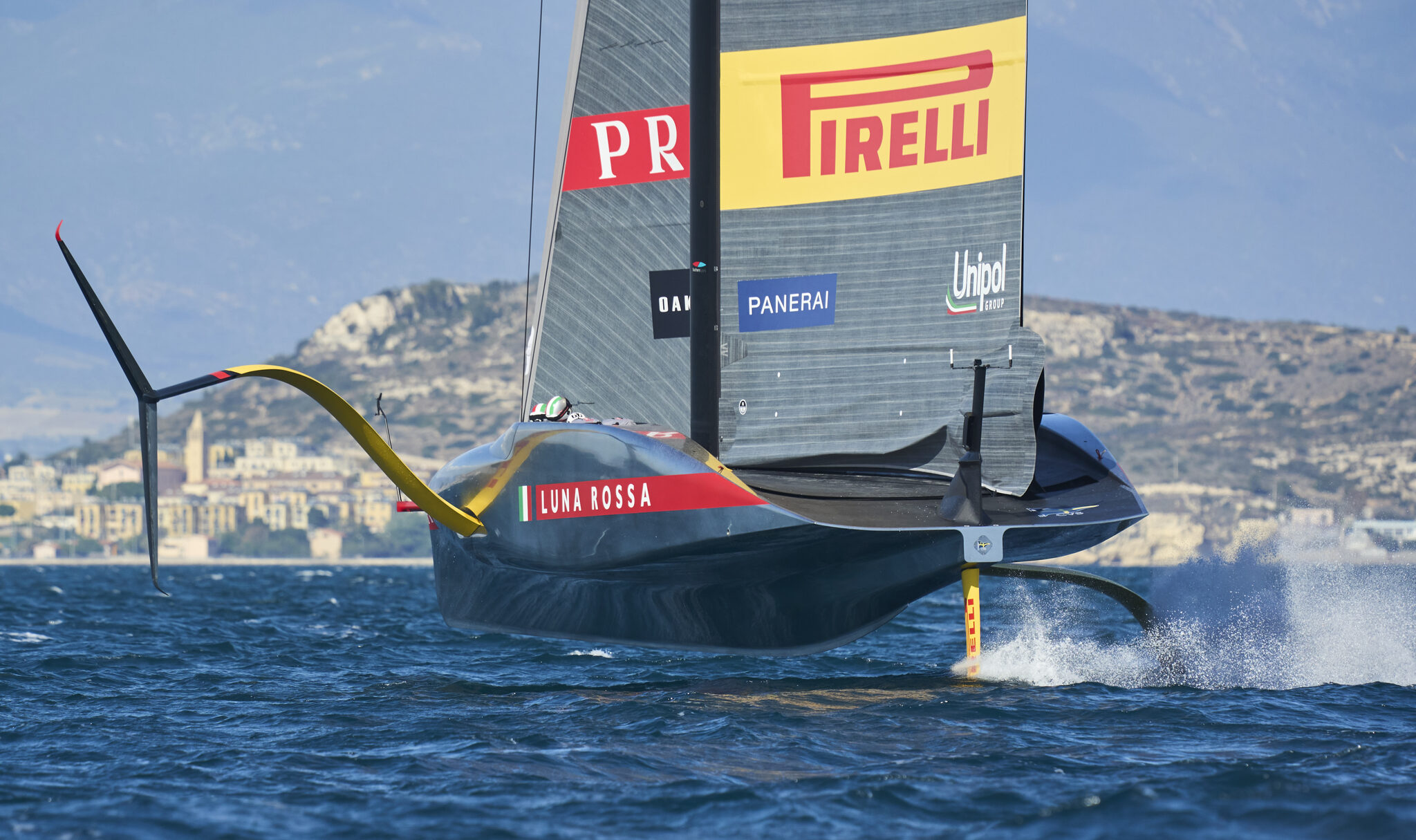 Una barca appoggio del team Pirelli Luna Rossa al fianco delle caravelle in alto mare.